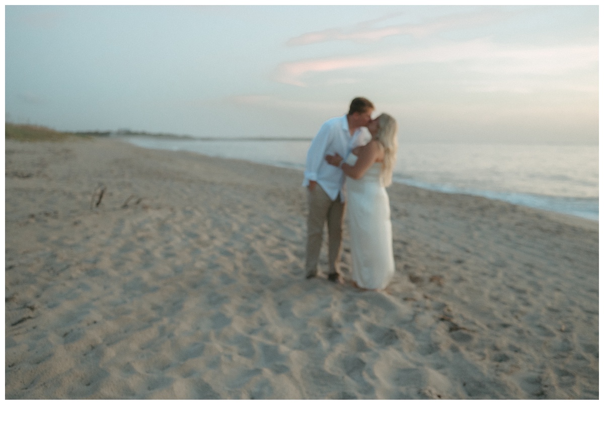 wide angle of couple kissing at sunrise on sebastian inlet beach in florida