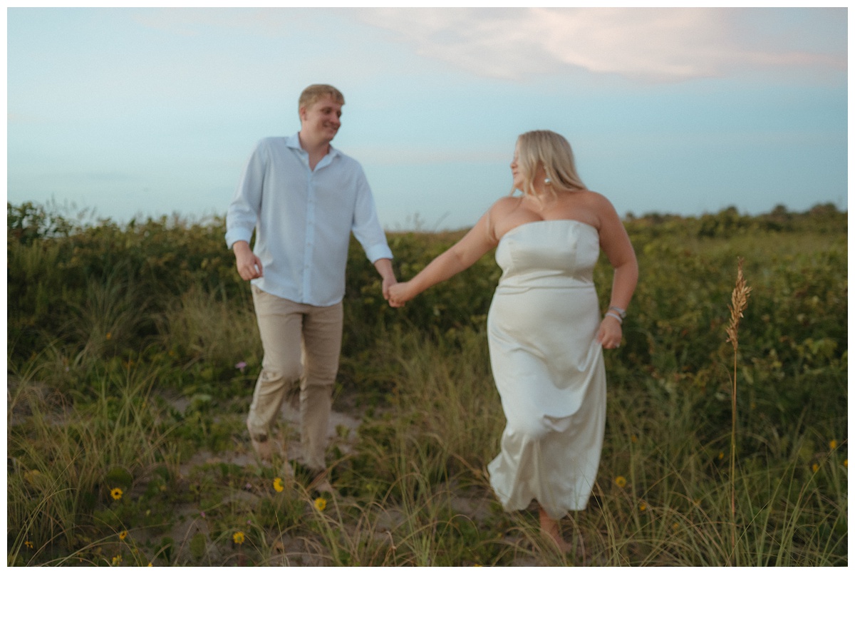 couple holding hands and walking through the brush at sebastian inlet beach during sunrise