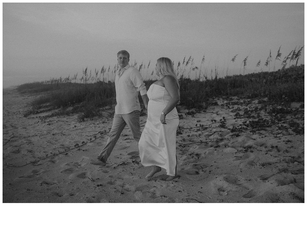 bride and groom walking down from berm at sebastian inlet beach after florida elopement in black and white