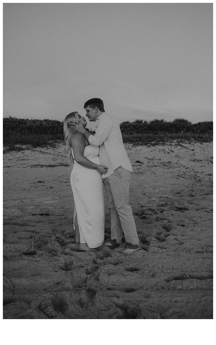 fun groom kissing bride in black and white photo