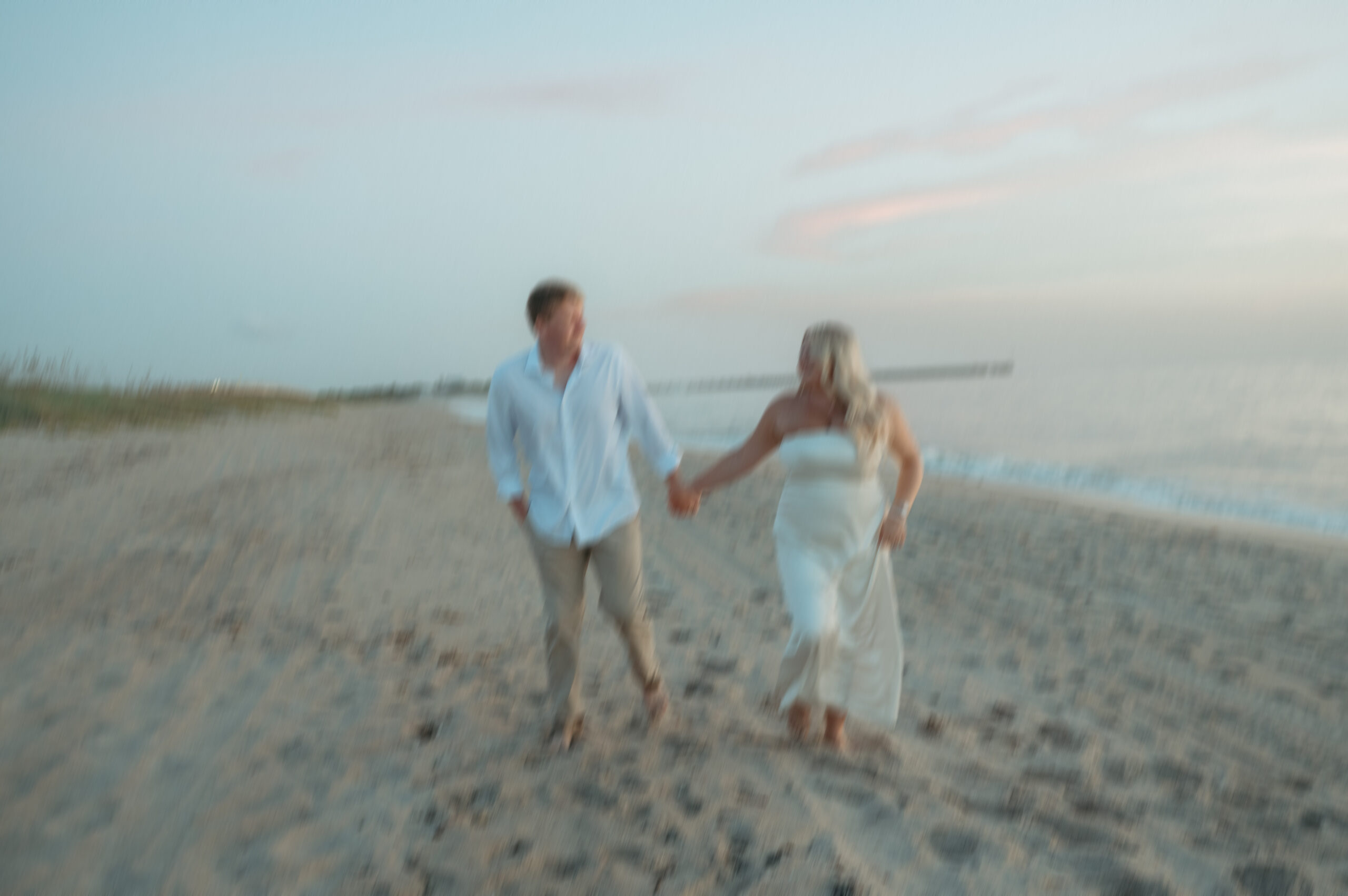 fun blurry moment with bride and groom running along sebastian inlet beach while holding hands