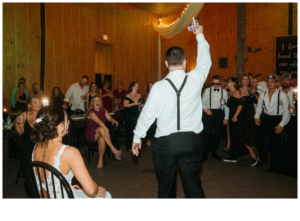 fun groom removing garter from bride during reception