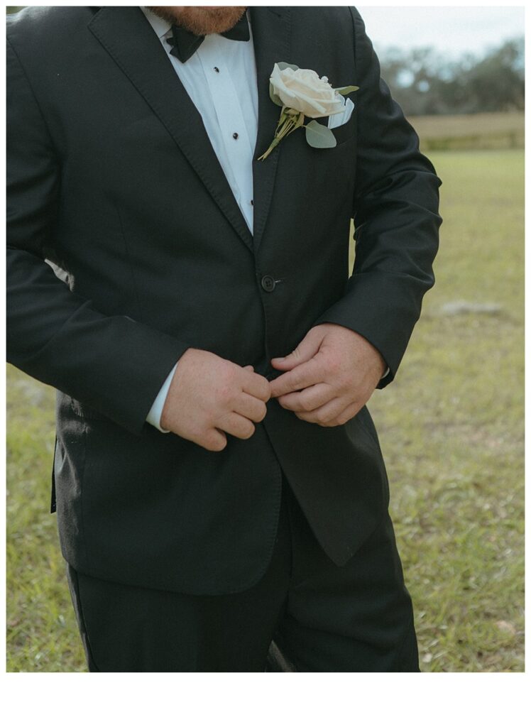 groom buttoning up suit jacket