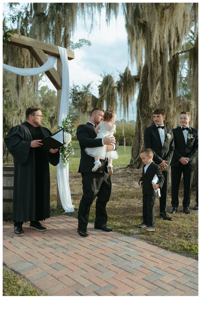 groom holding and hugging daughter during ceremony