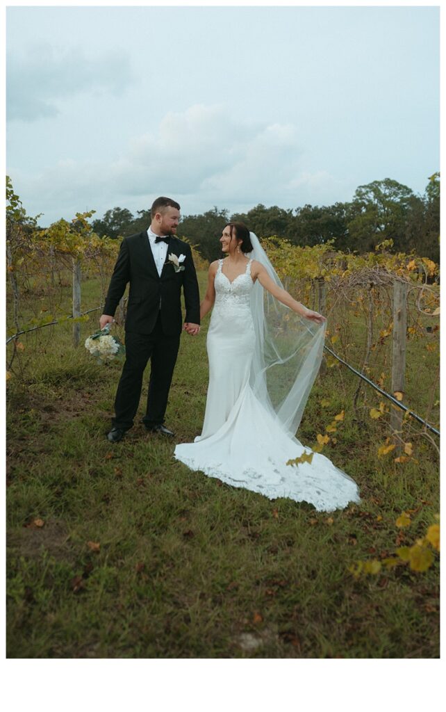 fun bride playing with veil and looking at groom