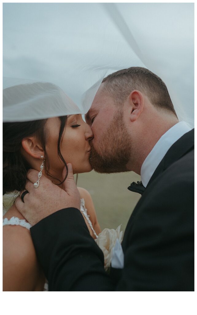 bride and groom kissing under veil