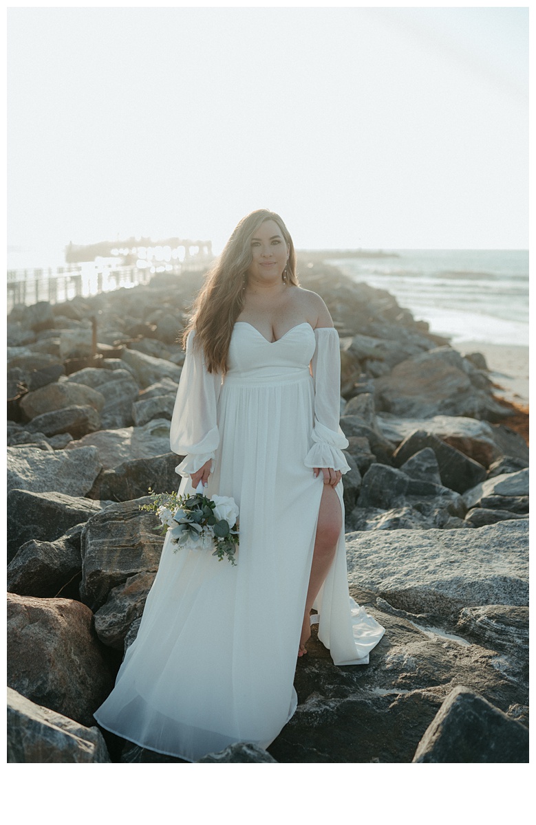 bride posing on jetty beach rocks