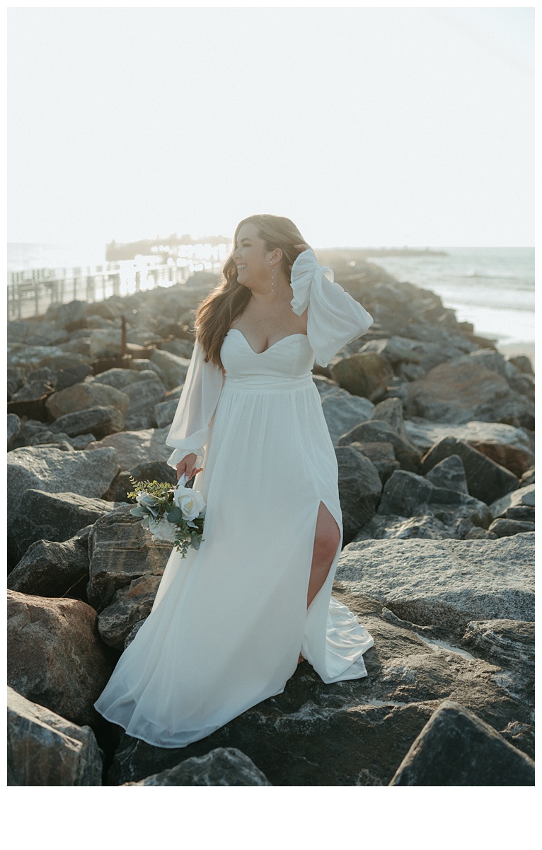 bride posing on jetty beach rocks