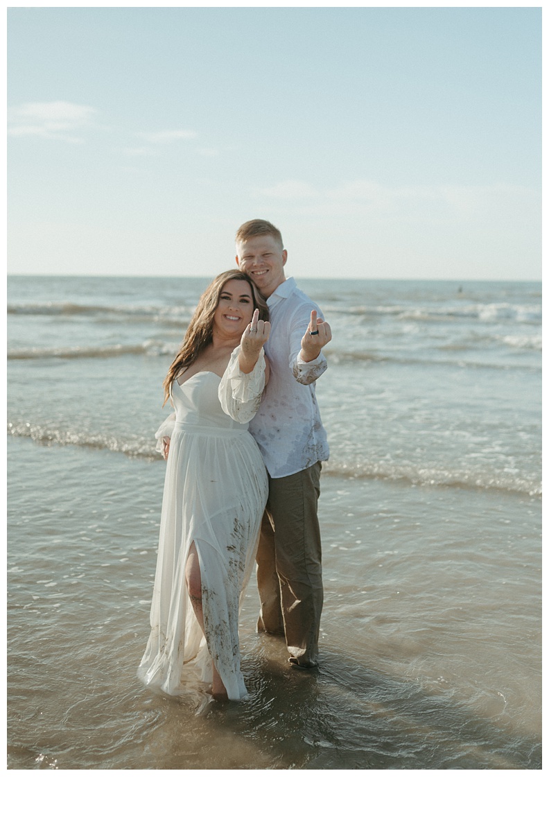 bride and groom showing off wedding rings on the beach