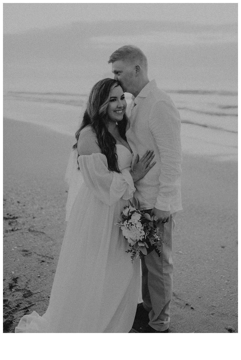 black and white bride smiling from groom kiss on temple