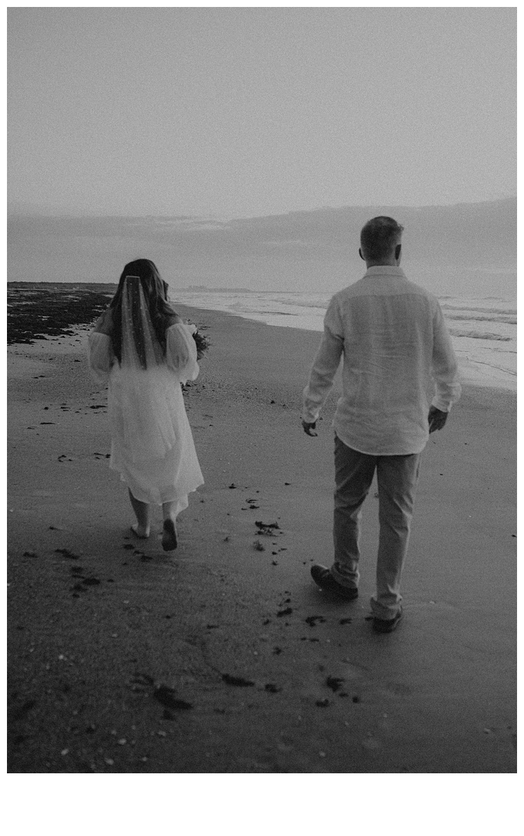 black and white newlyweds walking on beach