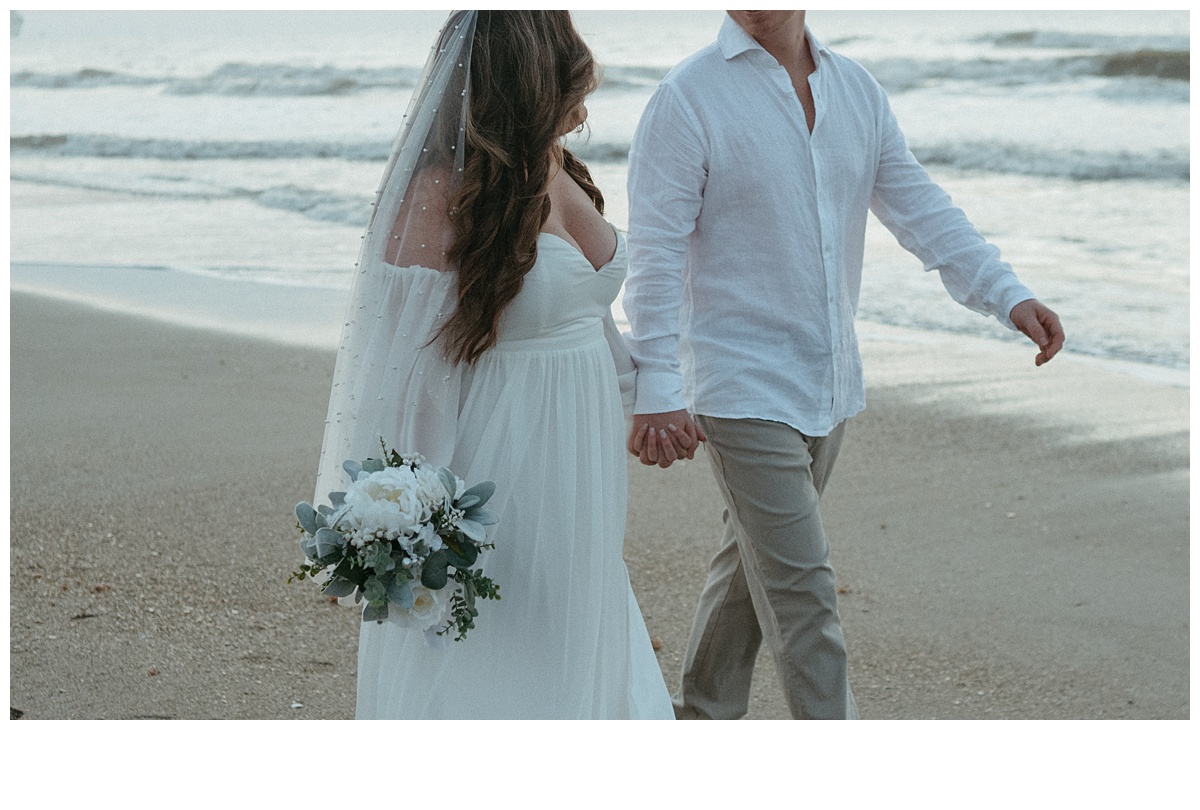 bride and groom holding hands walking onbeach