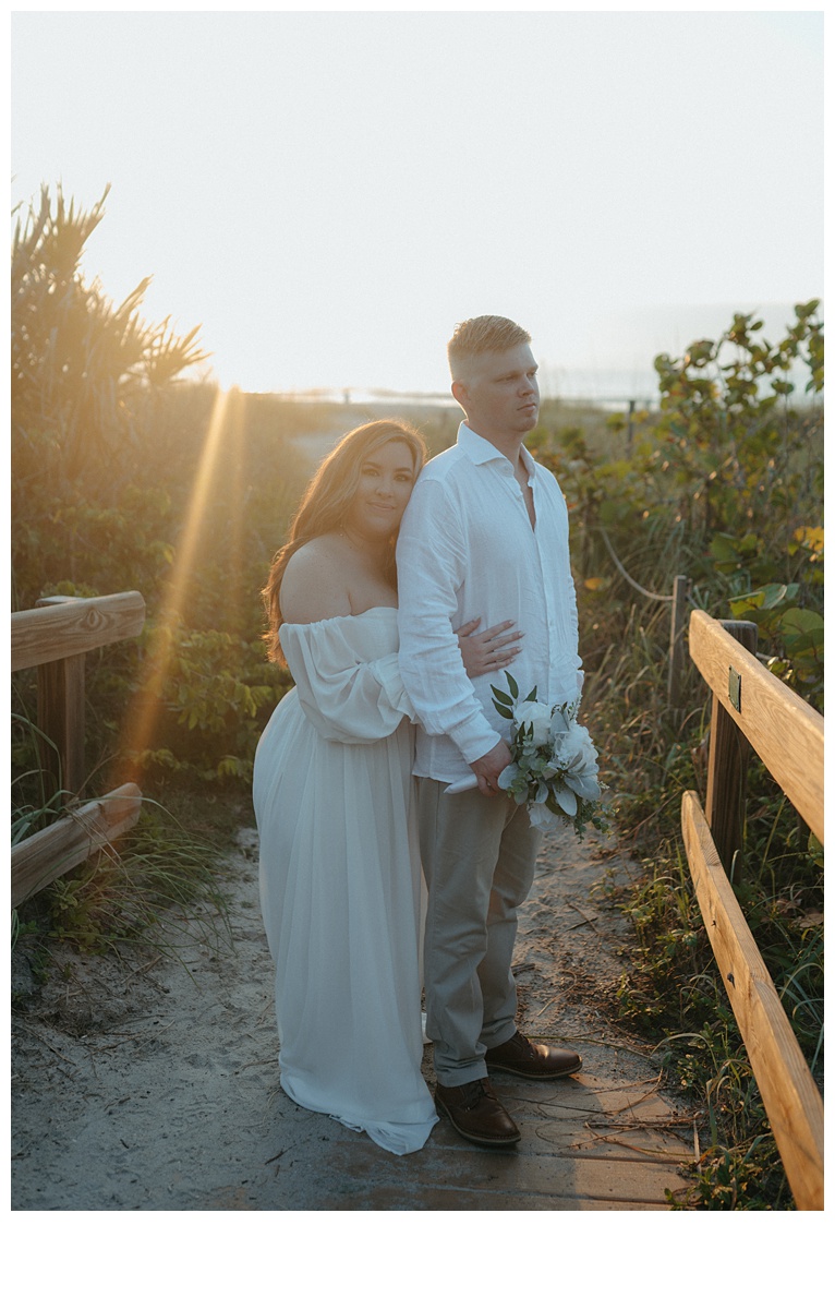 bride resting her head on grooms back at sunrise on beach