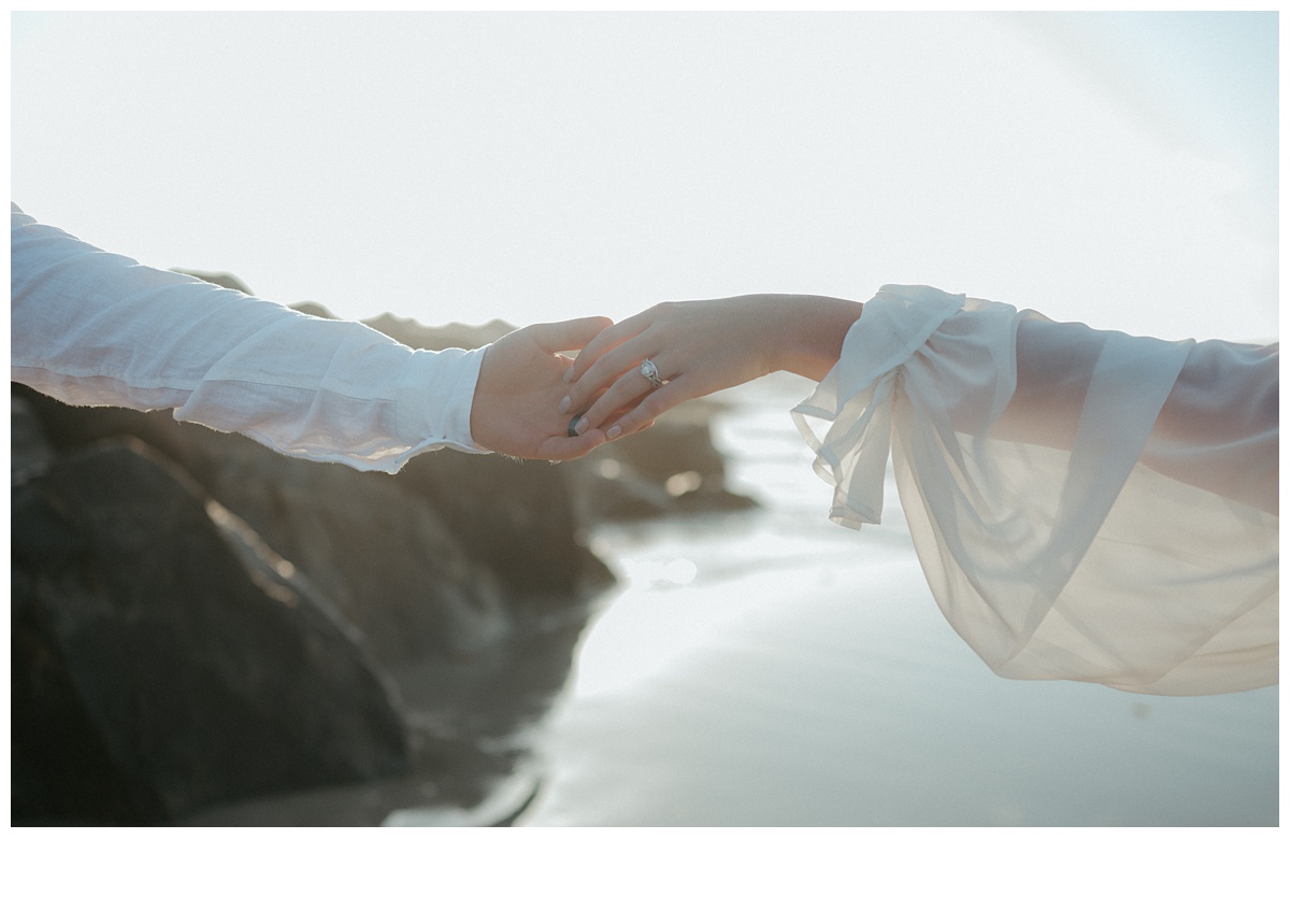 hands touching with jetty rocks in background