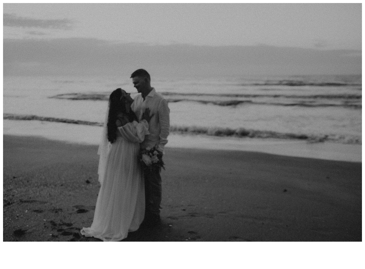 black and white moody bride and groom on beach