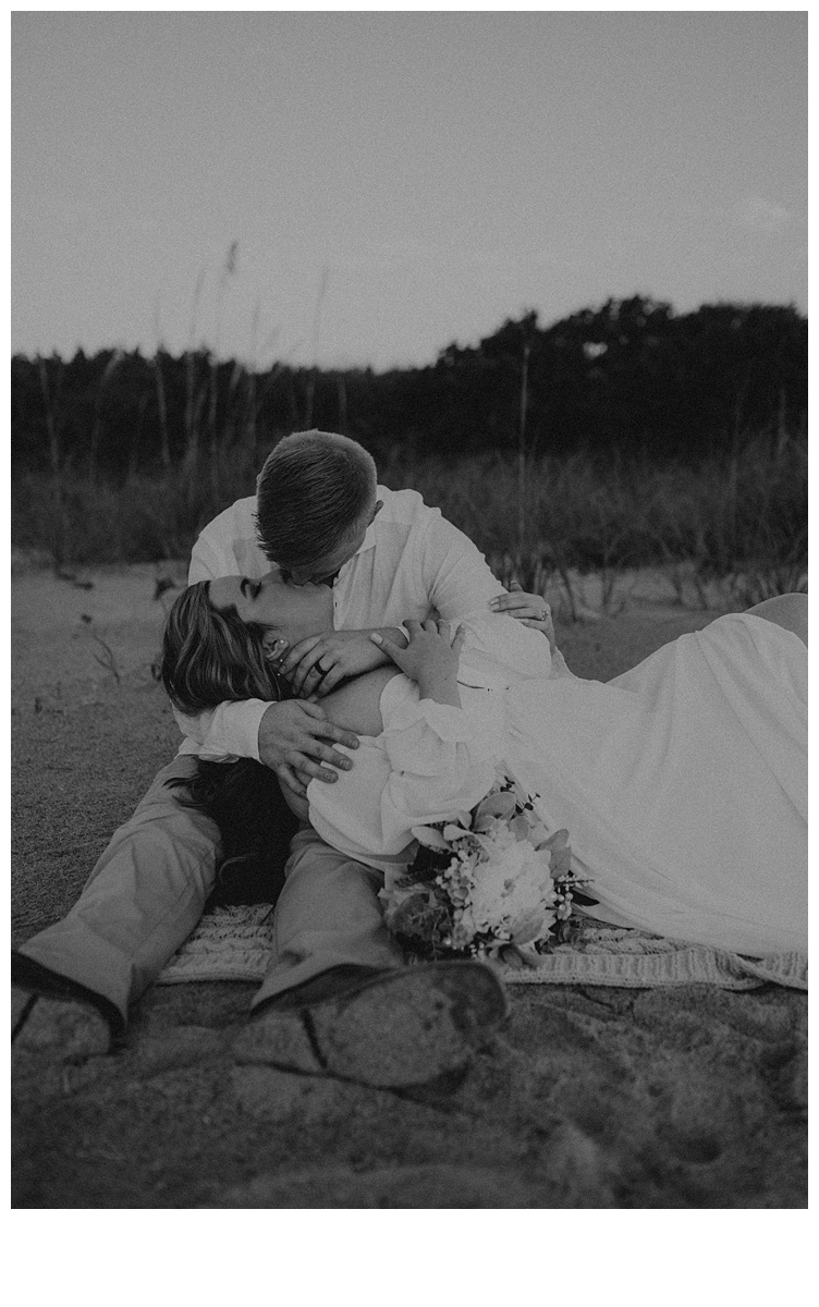 black and white romantic bride and groom kissing on the beach