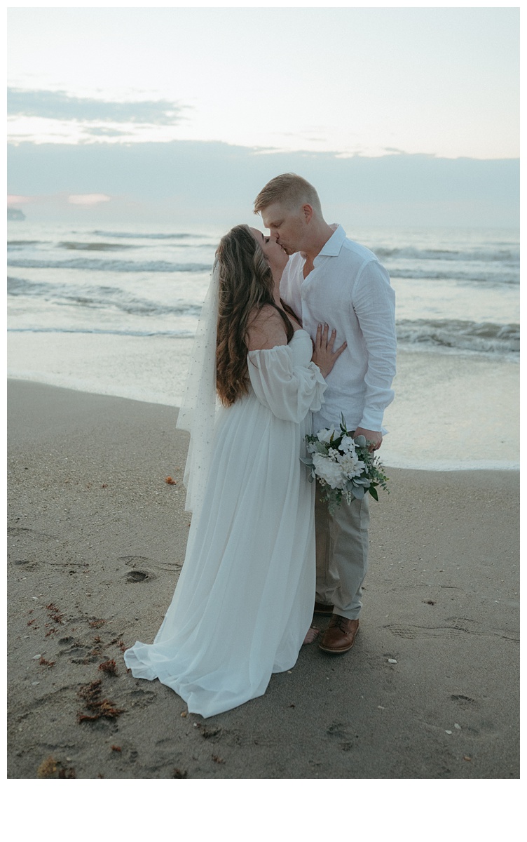 bride and groom share kiss on beach