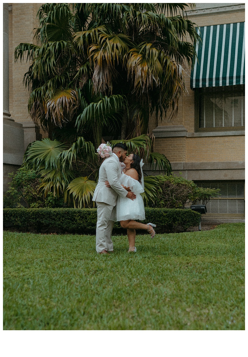 bride and groom kiss with a foot pop on lawn in downtown palm beach