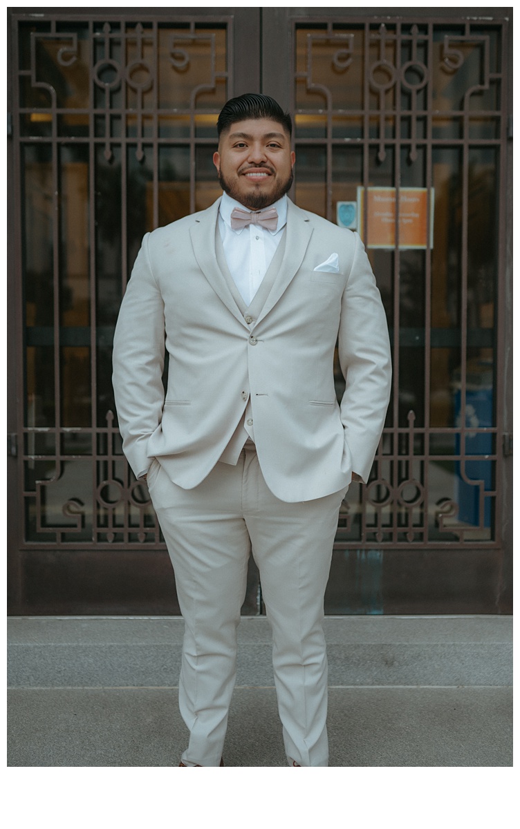 groom standing and posing in front of palm beach county courthouse brass doors