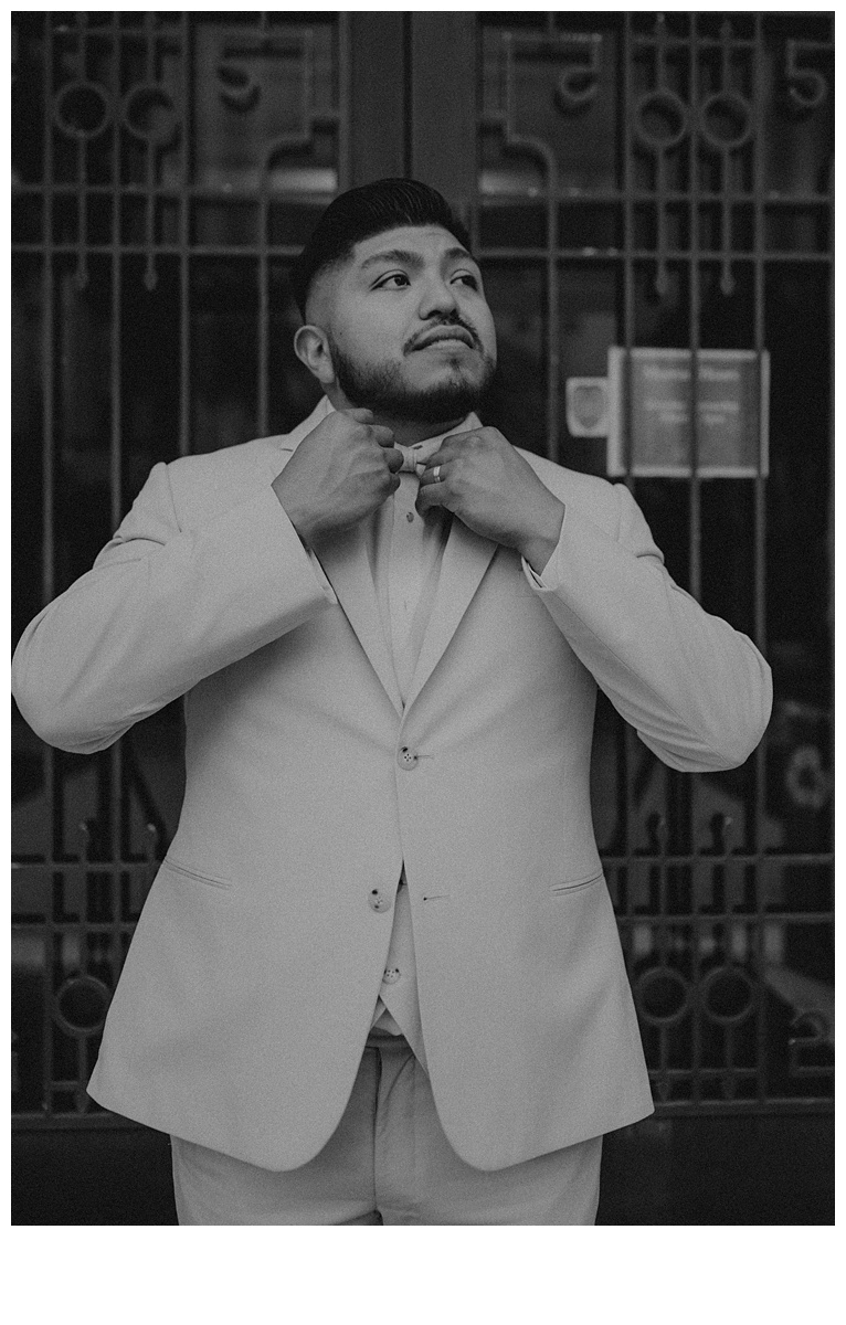 black and white photo groom fixes his bowtie