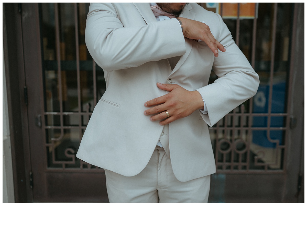 photo of groom adjusting pocket square with focus on his wedding band