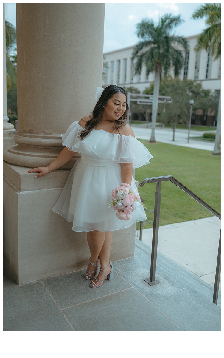 bride looks over her shoulder in fun pose on courthouse steps