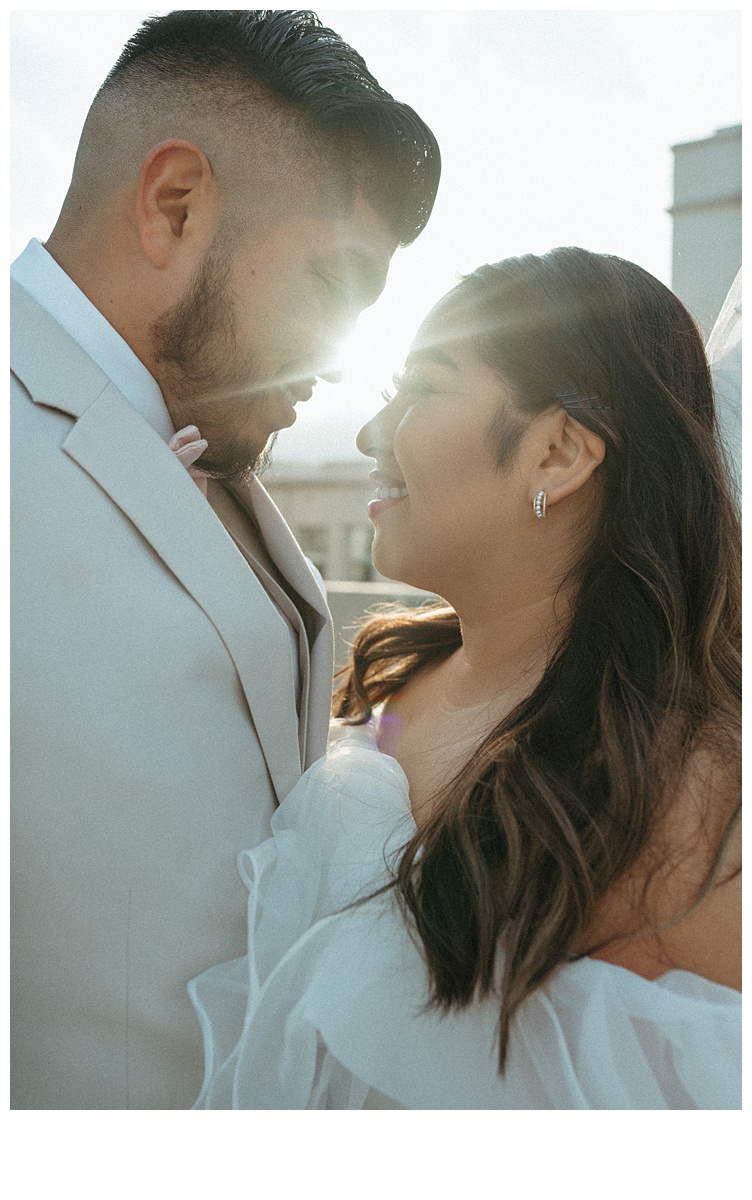 couple smiling at one another with golden sun peaking through