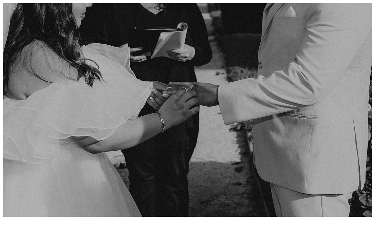 black and white bride putting ring on groom during ceremony