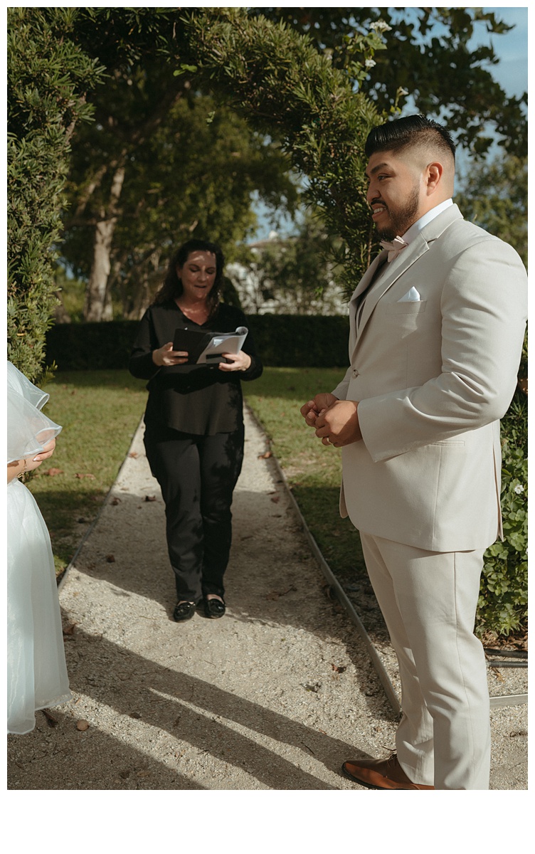 groom smiling while holding brides ring during ceremony 