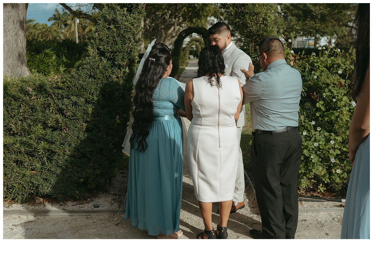 bride and groom parents praying over them after ceremony