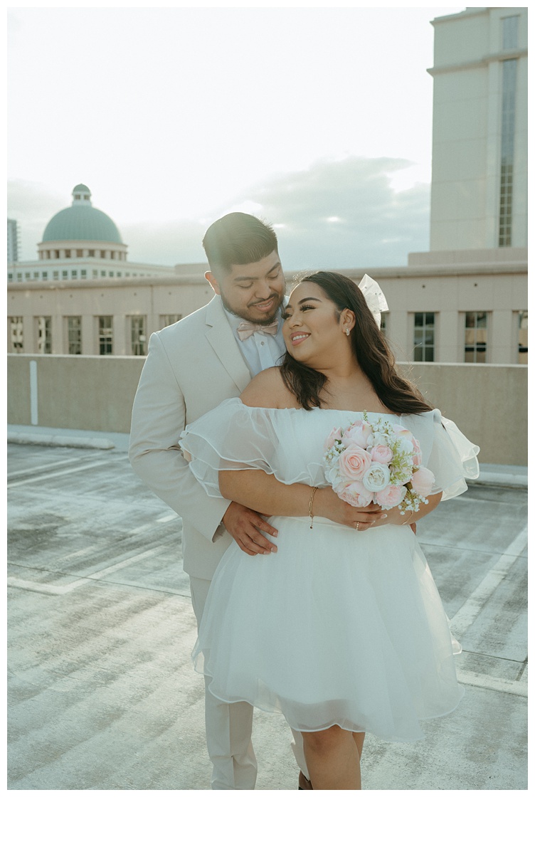 bride embraces groom on parking garage rooftop