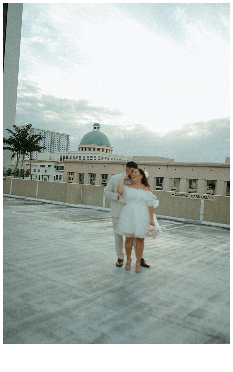 fun bride and groom blurred out while focus is on the downtown palm beach buildings