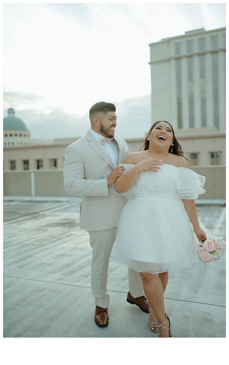 bride and groom laughing at grooms joke on parking garage rooftop