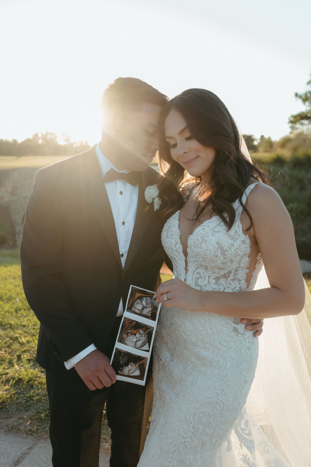 bride and groom golden hour portraits with a sonogram announcing their new baby